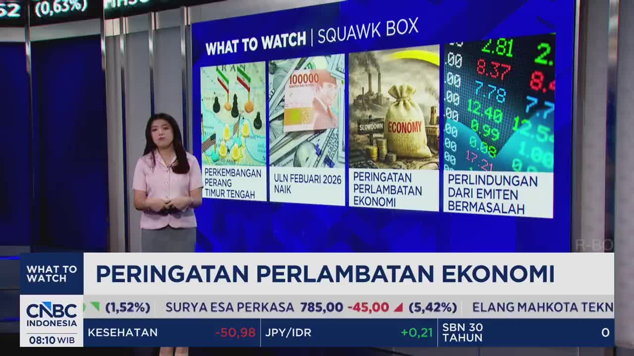 A woman in a pink shirt stands before a large screen displaying financial news from CNBC Indonesia. The screen shows four panels with headlines like "PERINGATAN PERLAMBATAN EKONOMI" (Economic Slowdown Warning) and stock market data. A woman in a pink shirt stands before a large screen displaying financial news from CNBC Indonesia. The screen shows four panels with headlines like "PERINGATAN PERLAMBATAN EKONOMI" (Economic Slowdown Warning) and stock market data.