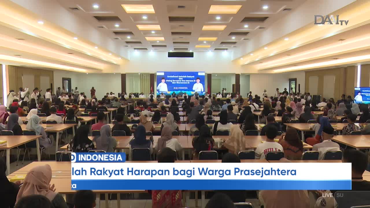 A large crowd fills the room, facing a screen that displays a presentation. The DAAI TV logo is visible, and a news banner at the bottom identifies the event as taking place in Indonesia.
