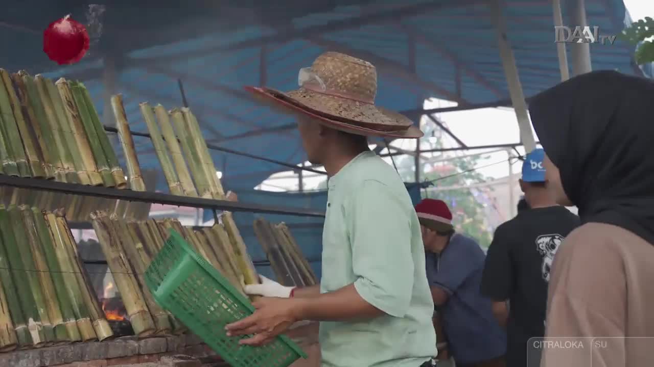 Bamboo tubes, filled with rice, are being grilled over an open fire. A man in a wide-brimmed hat carefully holds a green basket, ready to assist with the cooking process. Bamboo tubes, filled with rice, are being grilled over an open fire. A man in a wide-brimmed hat carefully holds a green basket, ready to assist with the cooking process.