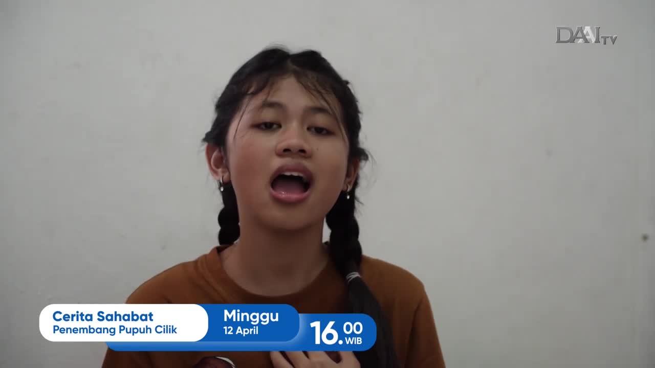 A young girl with braided hair sings into the camera. The DAAI TV logo appears in the upper right corner. A young girl with braided hair sings into the camera. The DAAI TV logo appears in the upper right corner.