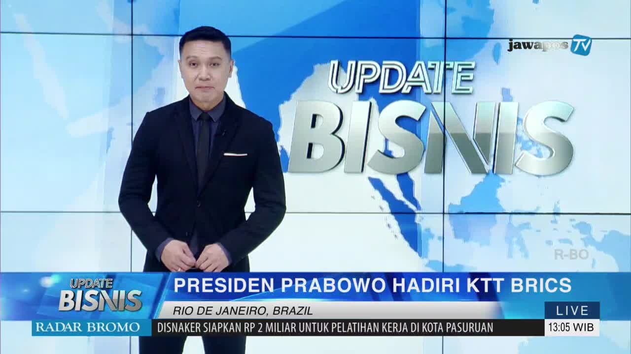 A man in a dark suit stands in front of a screen displaying the "Update Bisnis" segment logo from Jawa Pos TV. The news anchor is reporting live from Rio de Janeiro, Brazil, about President Prabowo's attendance at the KTT BRICS summit.

