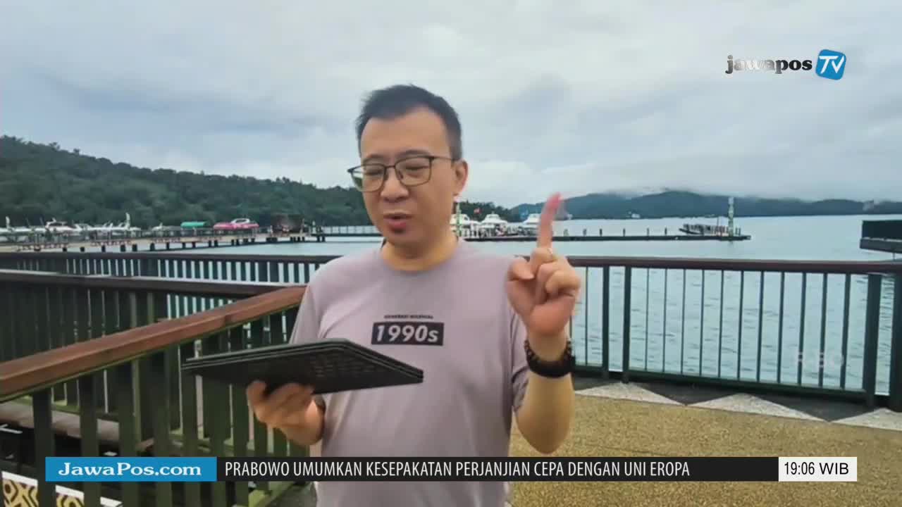 A man, holding a tablet, gestures towards the water as he speaks for Jawa Pos TV. The screen displays the news from Indonesia, with a headline about Prabowo.
