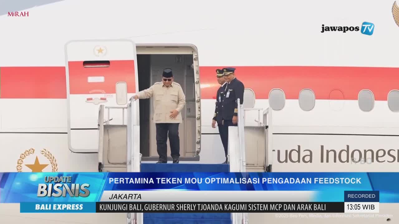 A man in a light-colored shirt and dark pants is stepping off a Garuda Indonesia plane, followed by two men in uniform. Jawa Pos TV's broadcast shows the news from Indonesia.
