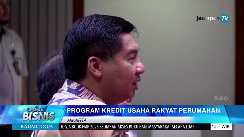 A man in a patterned shirt speaks, his face lit by the studio lights of Jawa Pos TV. Below, text on the screen announces a program about housing loans in Jakarta.
