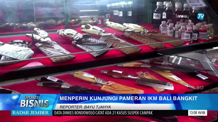 The Jawa Pos TV broadcast from Indonesia shows a display case filled with knives in leather sheaths. The news segment, "Update Bisnis," is reporting on a Bali IKM exhibition.
