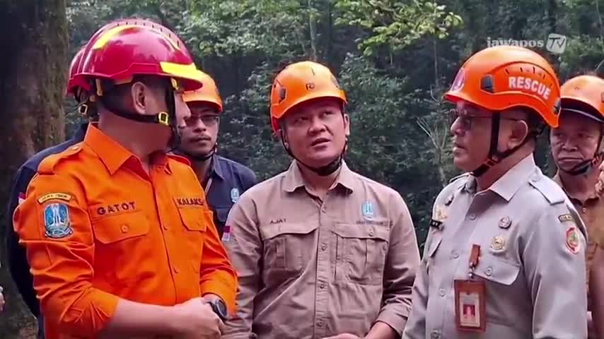 A group of men in helmets and uniforms are huddled together, speaking intently, likely discussing a situation. The Jawa Pos TV logo in the corner suggests this is a news report from Indonesia.
