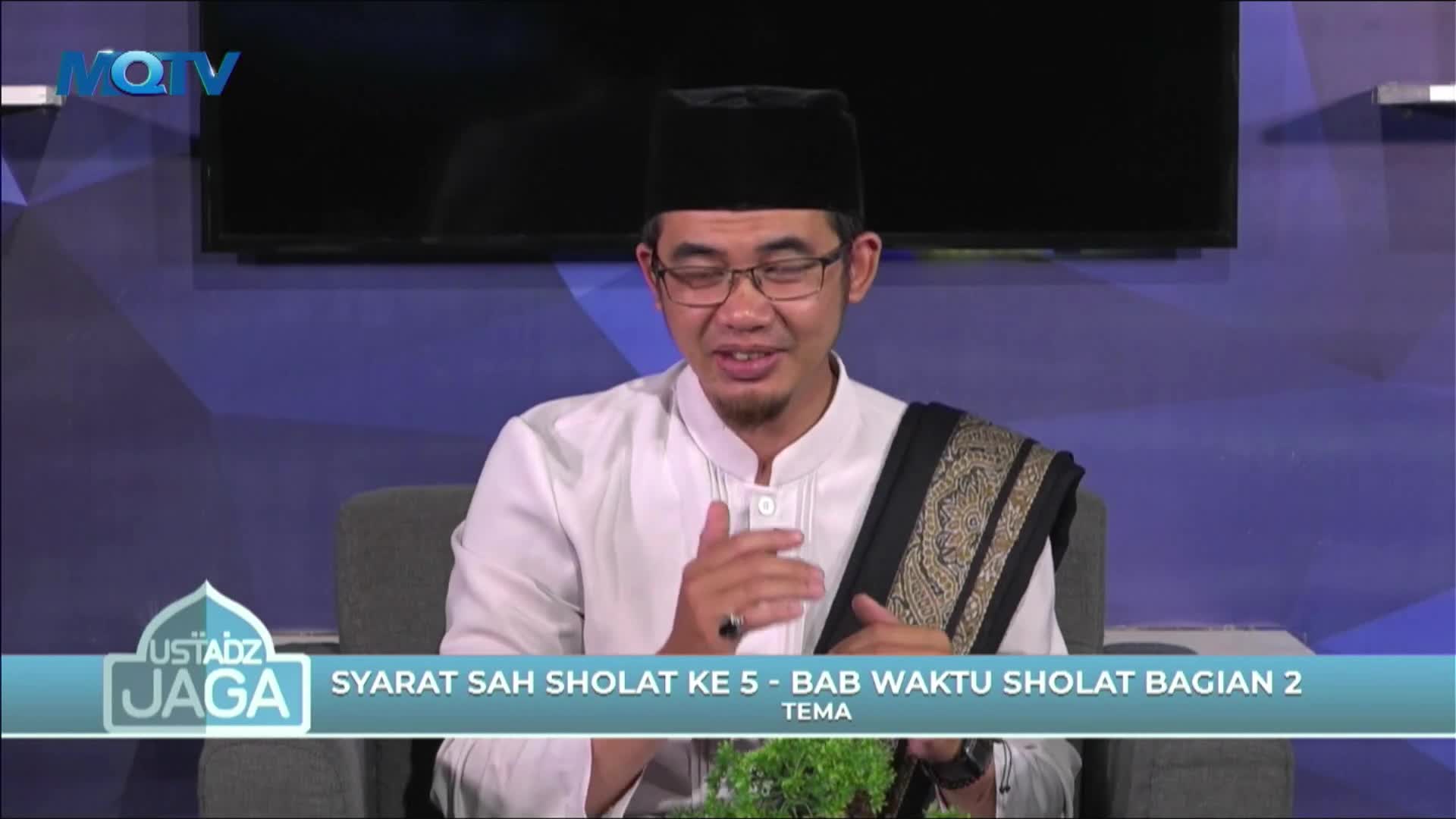 The man in the glasses gestures with his hands as he speaks, his white shirt and black cap a stark contrast to the blue background. He's on MQTV, discussing the requirements of prayer.
