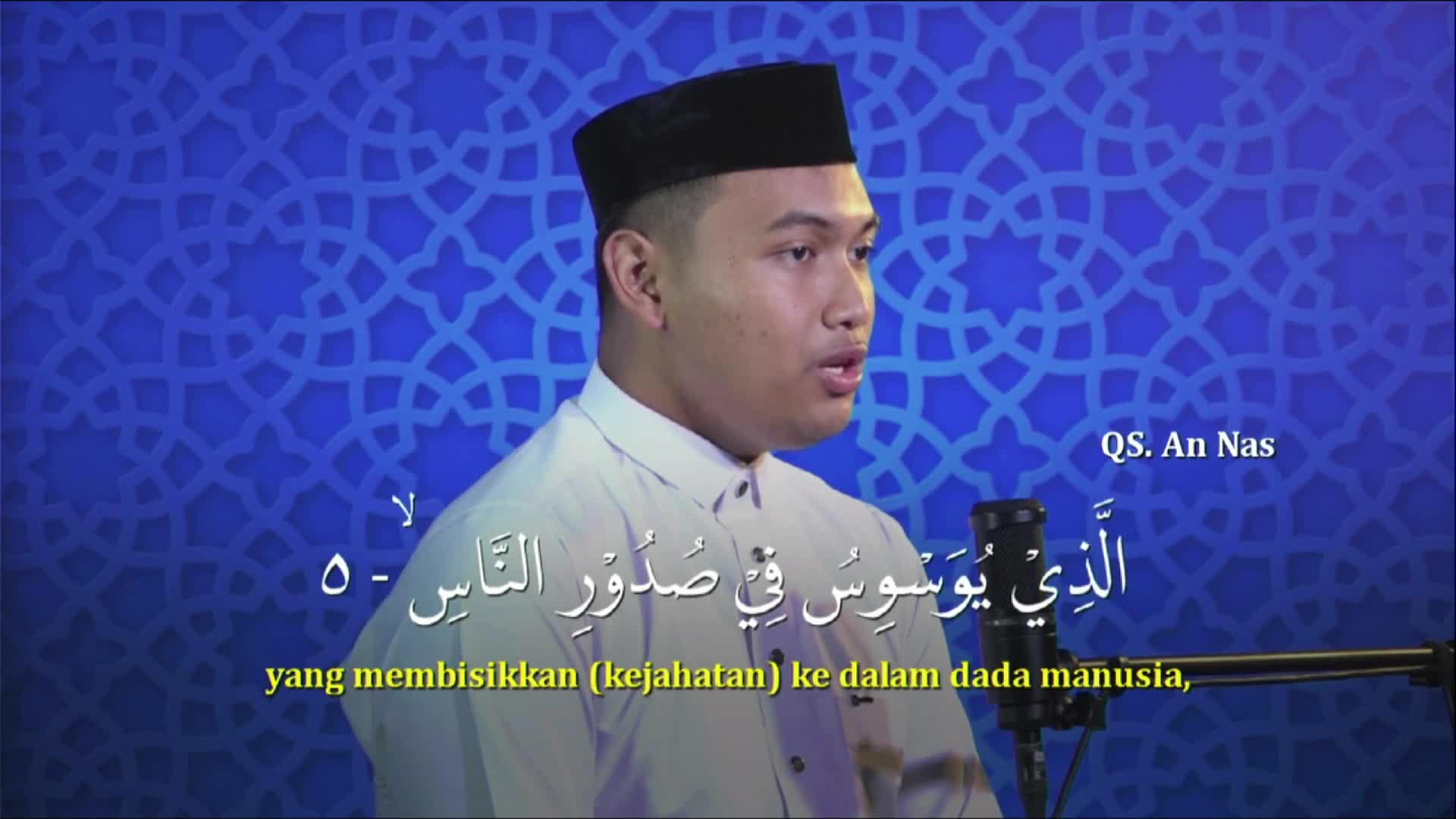 A young man in a white shirt and black cap is speaking into a microphone. The text on the screen, in Arabic and Indonesian, is from QS. An Nas.
