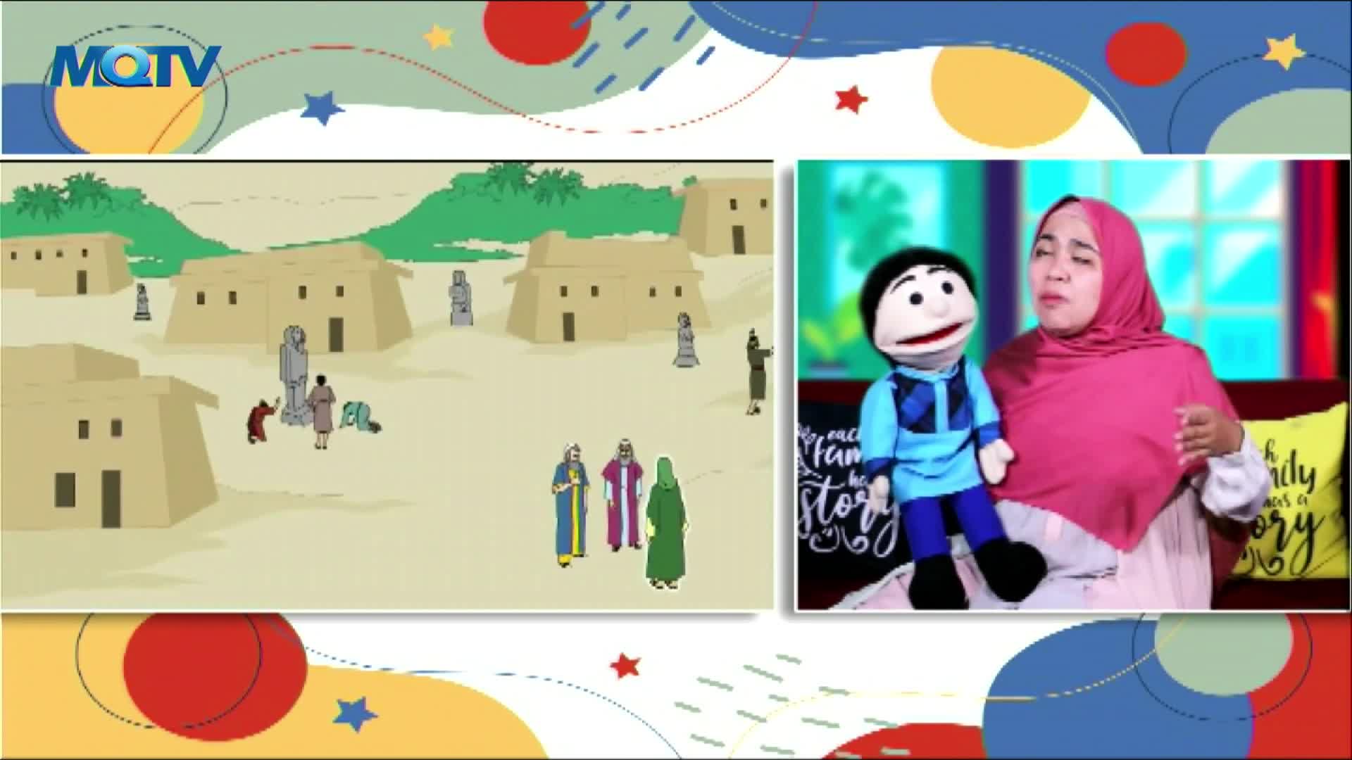 A cartoon scene of a desert village plays on the screen, while a woman in a pink hijab and a puppet sit together. The woman gestures as if telling a story on MQTV, an Indonesian children's program.
