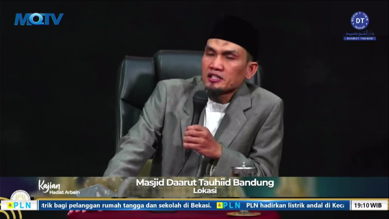 A man in a gray suit and black cap speaks into a microphone, his expression animated. The MQTV logo is visible, and the broadcast originates from Masjid Daarut Tauhiid in Bandung, Indonesia.
