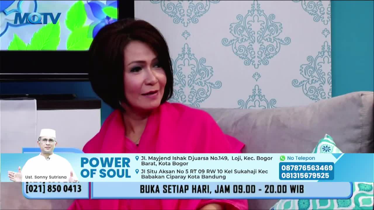 A woman in a bright pink top gestures as she speaks on the MQTV set. A graphic with the words "Power of Soul" and contact information for a spiritual service runs along the bottom of the screen.

