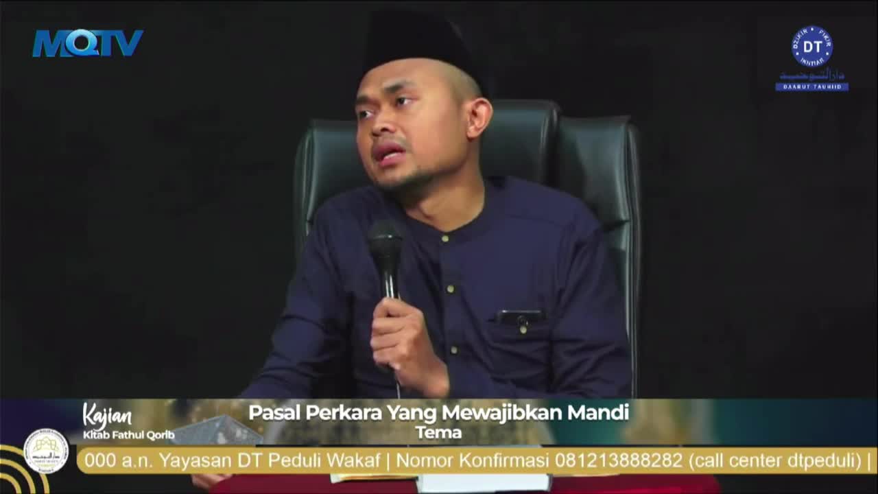 A man wearing a black cap and a blue shirt speaks into a microphone, his gaze directed somewhere off-camera. The MQTV logo is visible in the top left corner, and text at the bottom indicates the topic is about ritual bathing.

