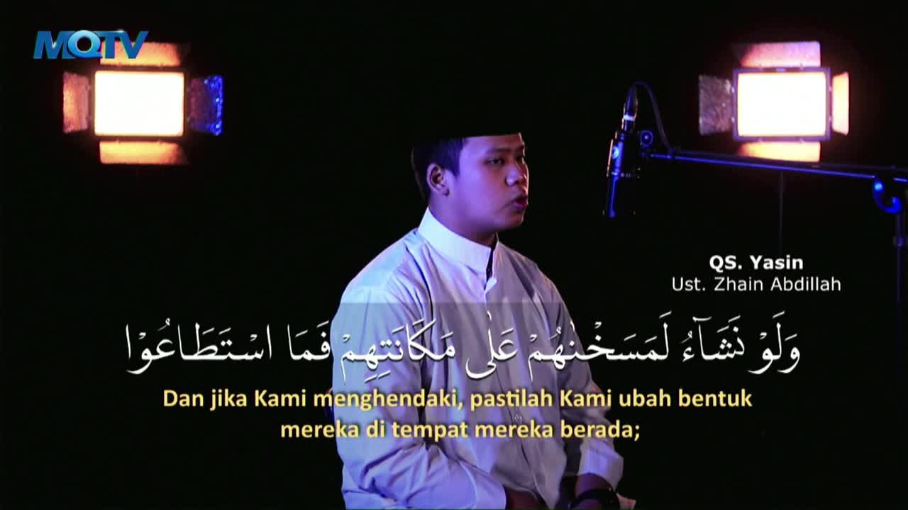 A man in a white shirt and black cap speaks into a microphone, his face illuminated by studio lights. Below him, Arabic script and its Indonesian translation appear on screen, identifying the program as MQTV.
