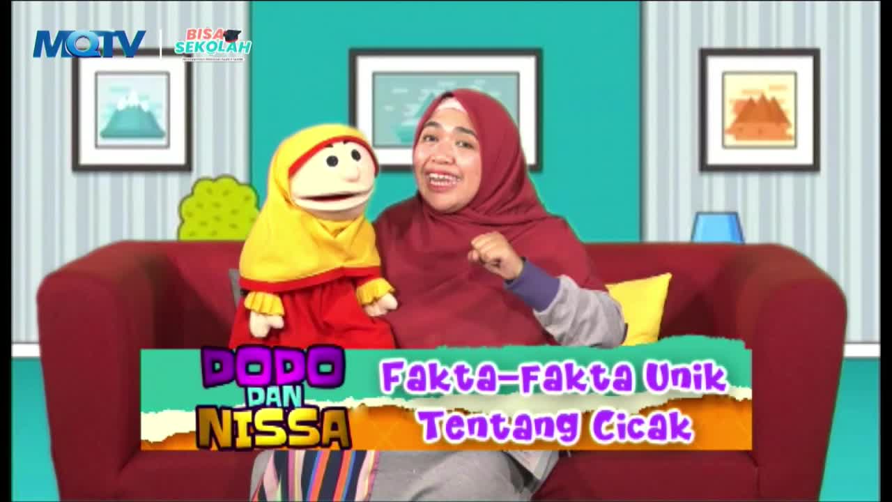 A woman in a maroon hijab and a puppet sit on a red couch, both smiling. They're on an MQTV show called "Dodo dan Nissa," discussing unique facts about geckos.
