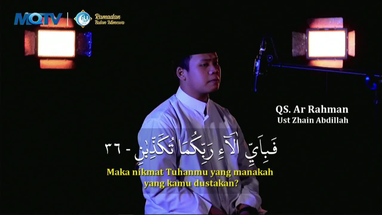 A man in a white robe recites from the Quran, illuminated by soft lights. Arabic script and Indonesian translation appear on screen, identifying the verse and speaker.
