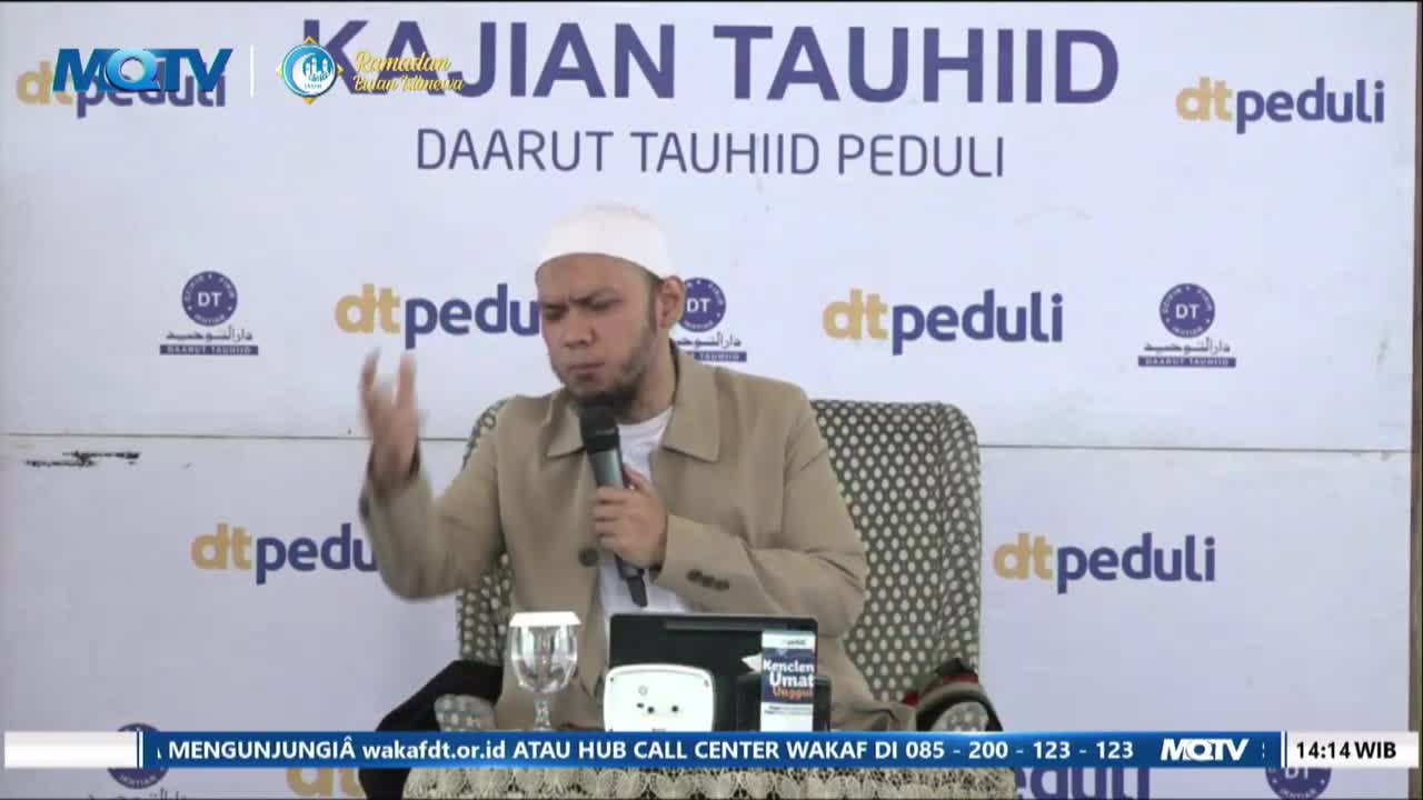 A man in a white cap and tan jacket gestures with his right hand while speaking into a microphone. Behind him, a banner displays "KAJIAN TAUHIID DAARUT TAUHIID PEDULI" and the MQTV logo.
