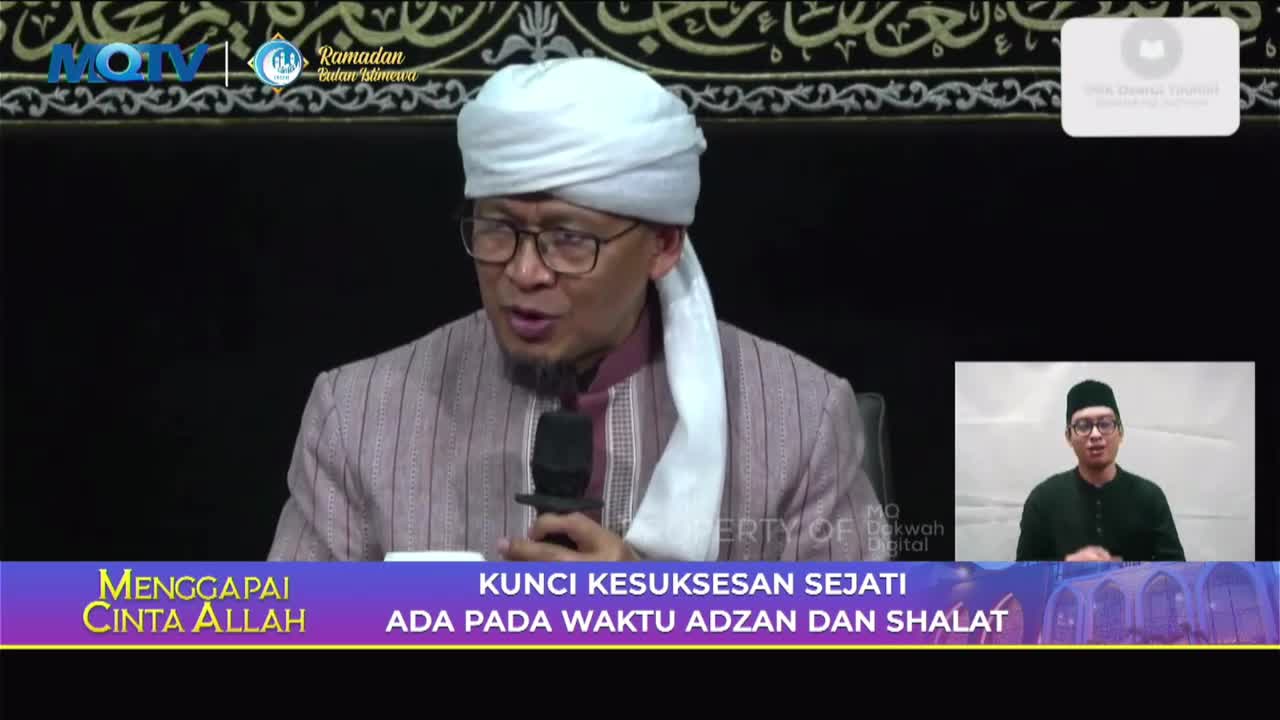 A man in a white turban and striped robe speaks into a microphone. A smaller screen shows another man in a black cap and shirt. The bottom of the screen displays text in Indonesian. A man in a white turban and striped robe speaks into a microphone. A smaller screen shows another man in a black cap and shirt. The bottom of the screen displays text in Indonesian.