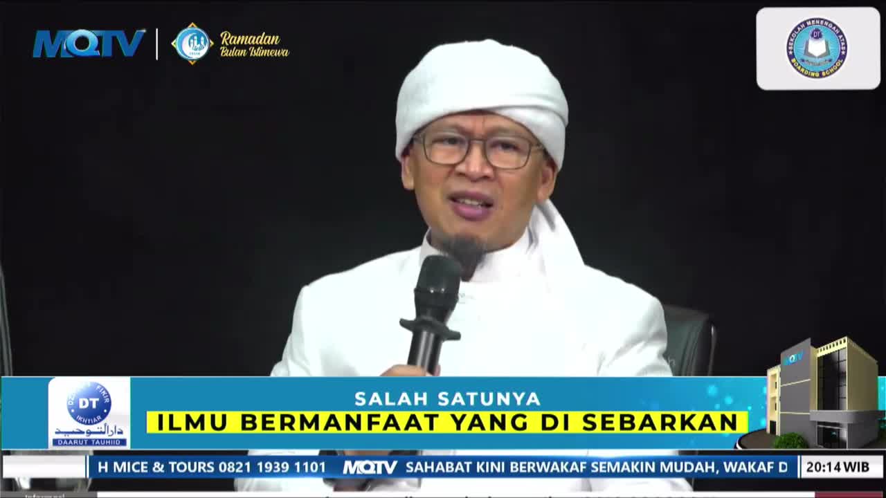 A man in a white peci and robe speaks into a microphone, his glasses reflecting the light. The MQTV logo and Indonesian text appear on screen, indicating a broadcast from Indonesia.