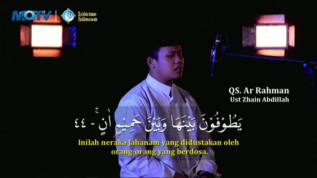 A man in a white shirt and peci recites from the Quran, his voice amplified by a microphone. Arabic script and Indonesian subtitles appear on screen, identifying the recitation as from QS. Ar Rahman by Ust. Zhain Abdillah.