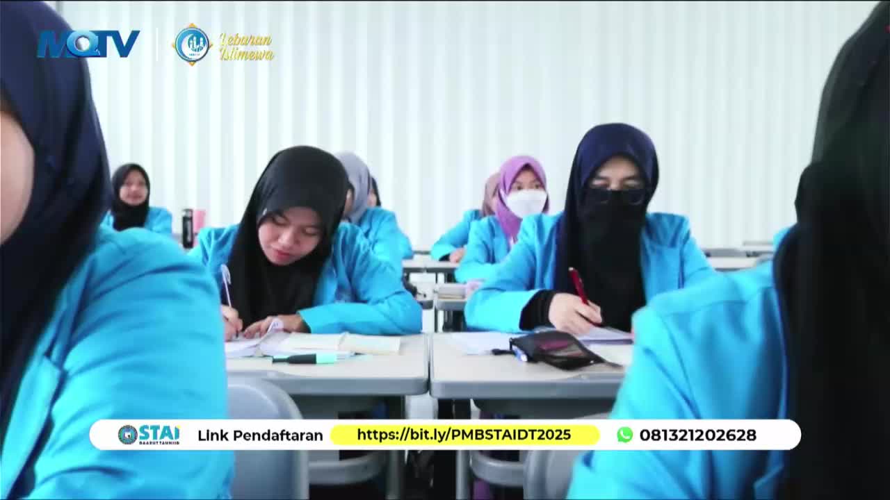Students in bright blue jackets and headscarves concentrate on their papers, pens in hand. The MQTV logo appears in the corner, a reminder of the broadcast.