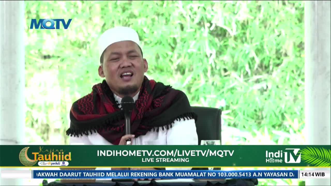 A man in a white peci and a red and black scarf speaks into a microphone, his mouth open mid-sentence. The MQTV logo appears in the upper left corner.