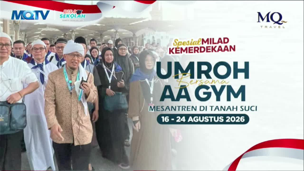A group of people, many wearing white peci hats and Islamic attire, walk together under a covered walkway. A man in a patterned jacket holds a walkie-talkie, leading the procession.