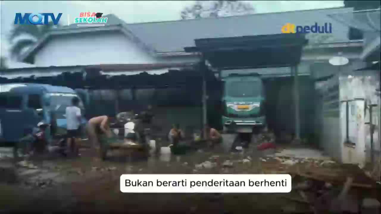 A blue truck sits parked, and a few people are gathered around, some tending to what looks like a fire. A green truck is parked further back under a shelter.