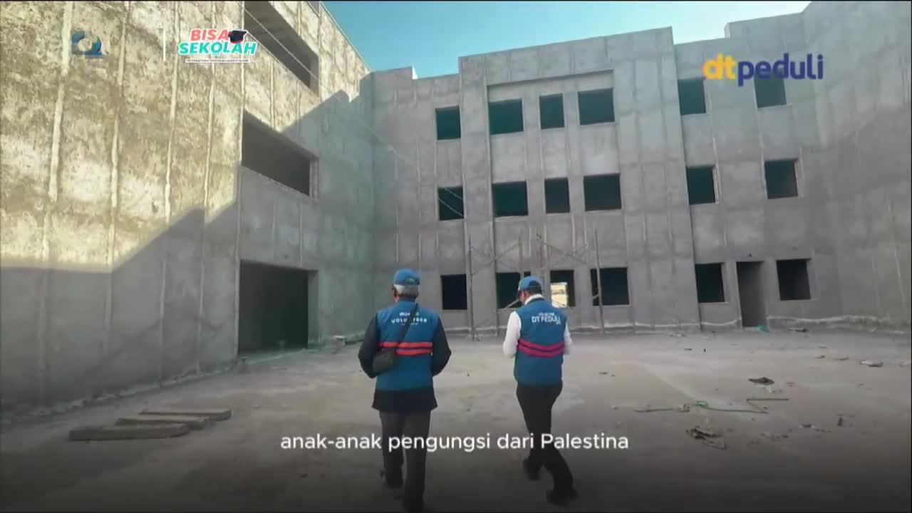 Two men in blue vests walk towards a large, unfinished concrete building. The text on their vests indicates they are from MQTV, here to help Palestinian refugee children.