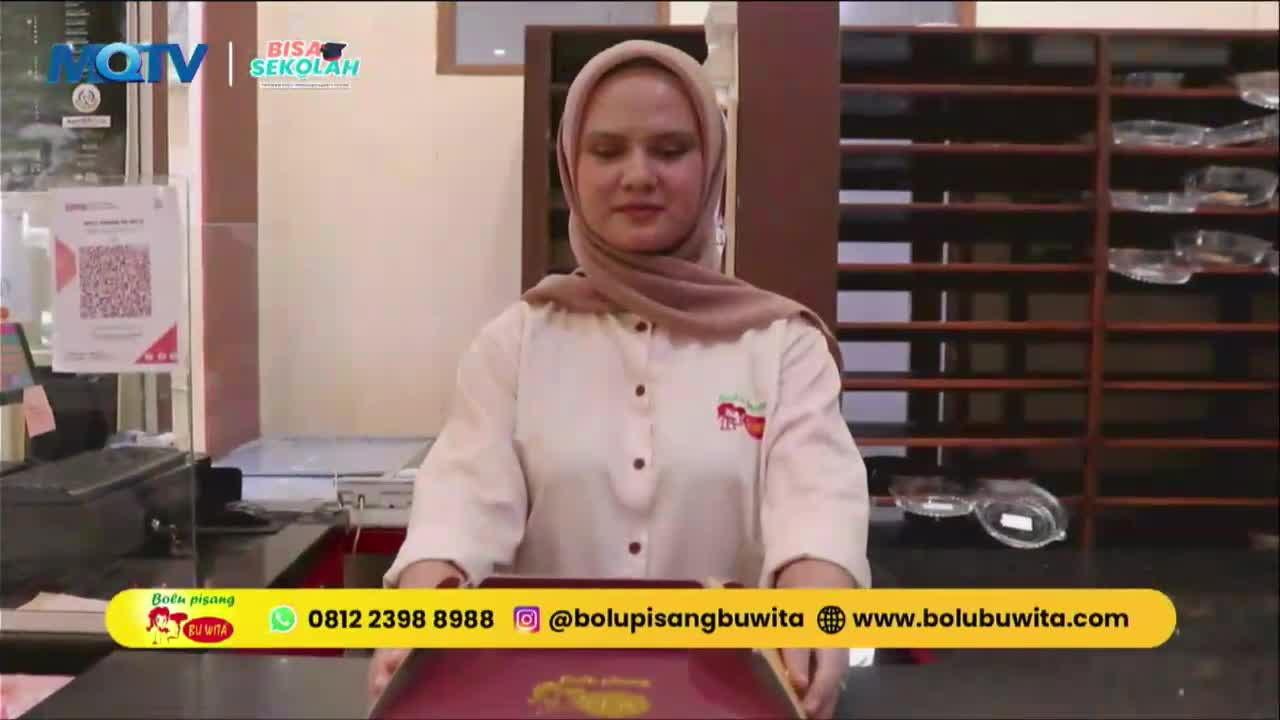 A woman in a hijab holds a rectangular tray, her hands steady as she presents it. The MQTV logo is visible in the upper left corner.