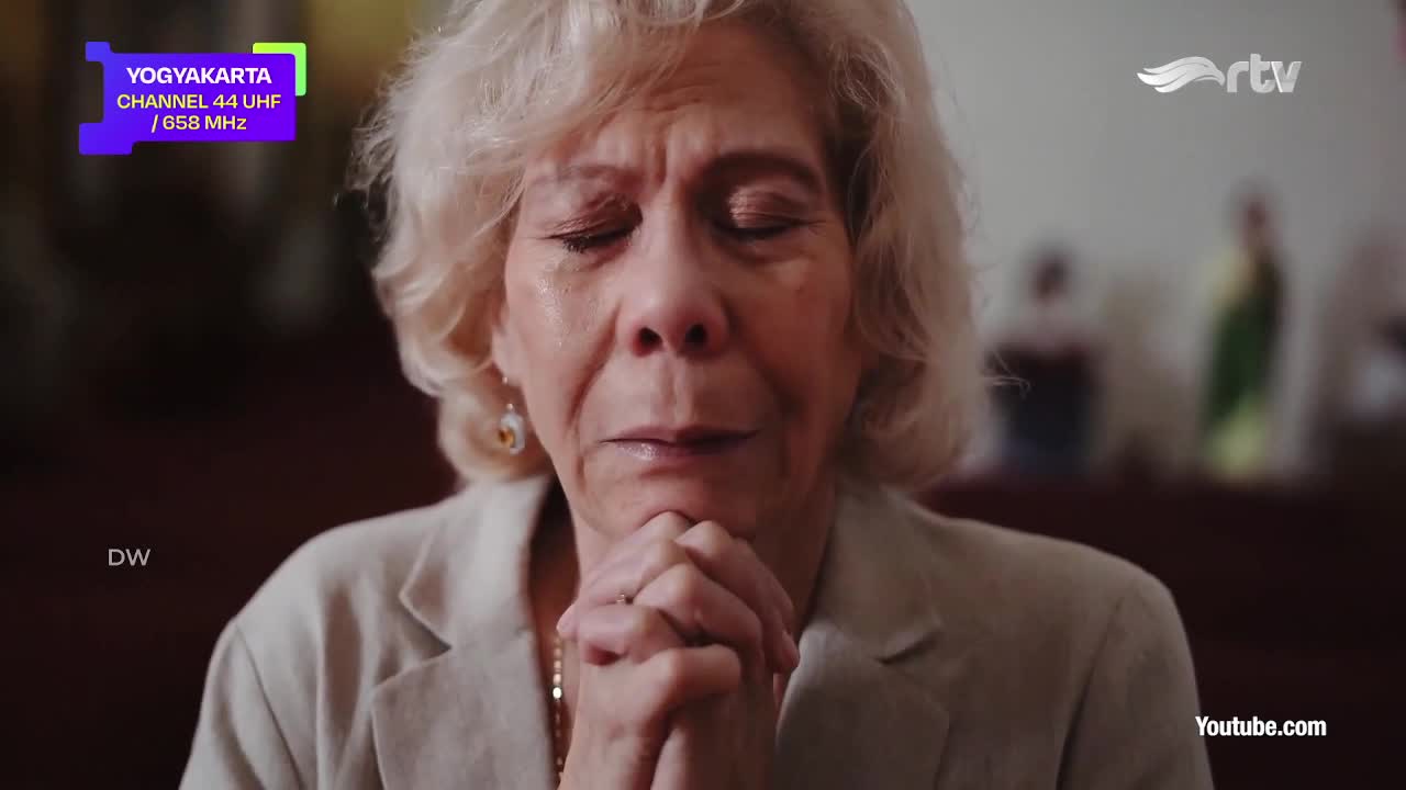 A woman with wet cheeks and closed eyes clasps her hands in front of her, seemingly in prayer. The Rajawali TV logo and Yogyakarta channel information are visible in the corner.
