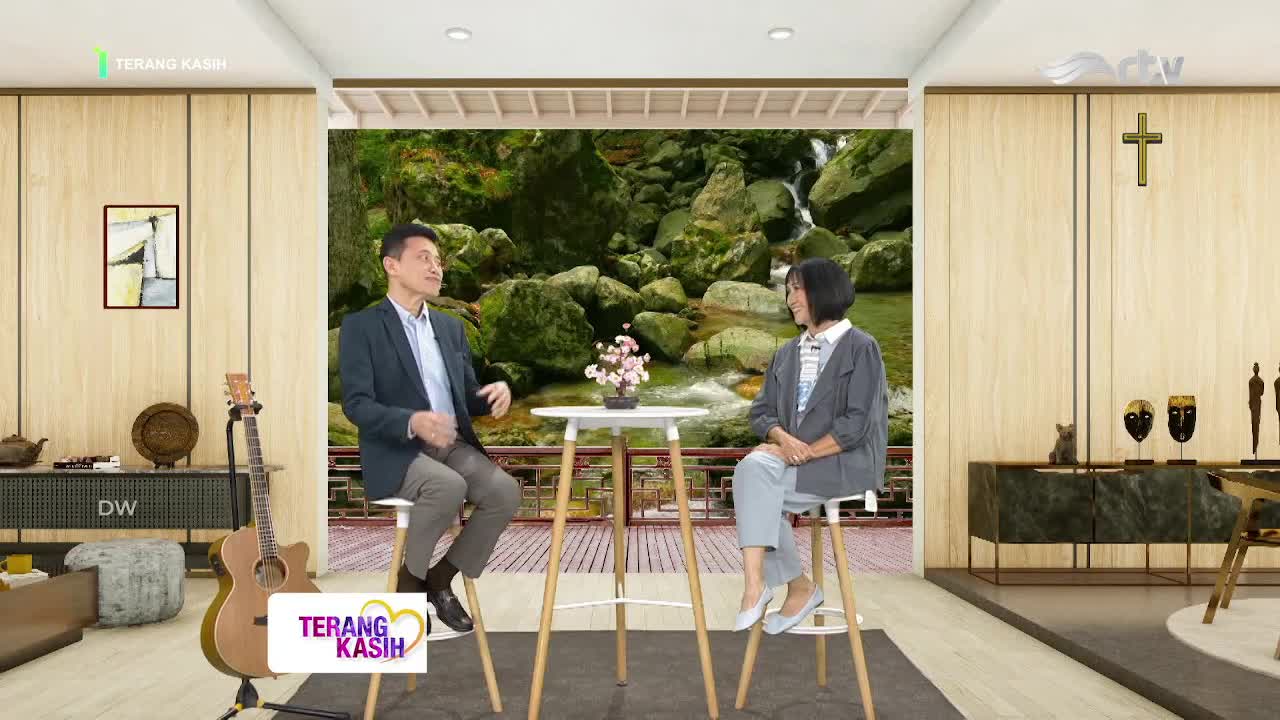 The man and woman are seated on stools, engaged in a conversation in front of a scenic backdrop. The "Terang Kasih" logo is visible, suggesting this is a program on Rajawali TV in Indonesia.

