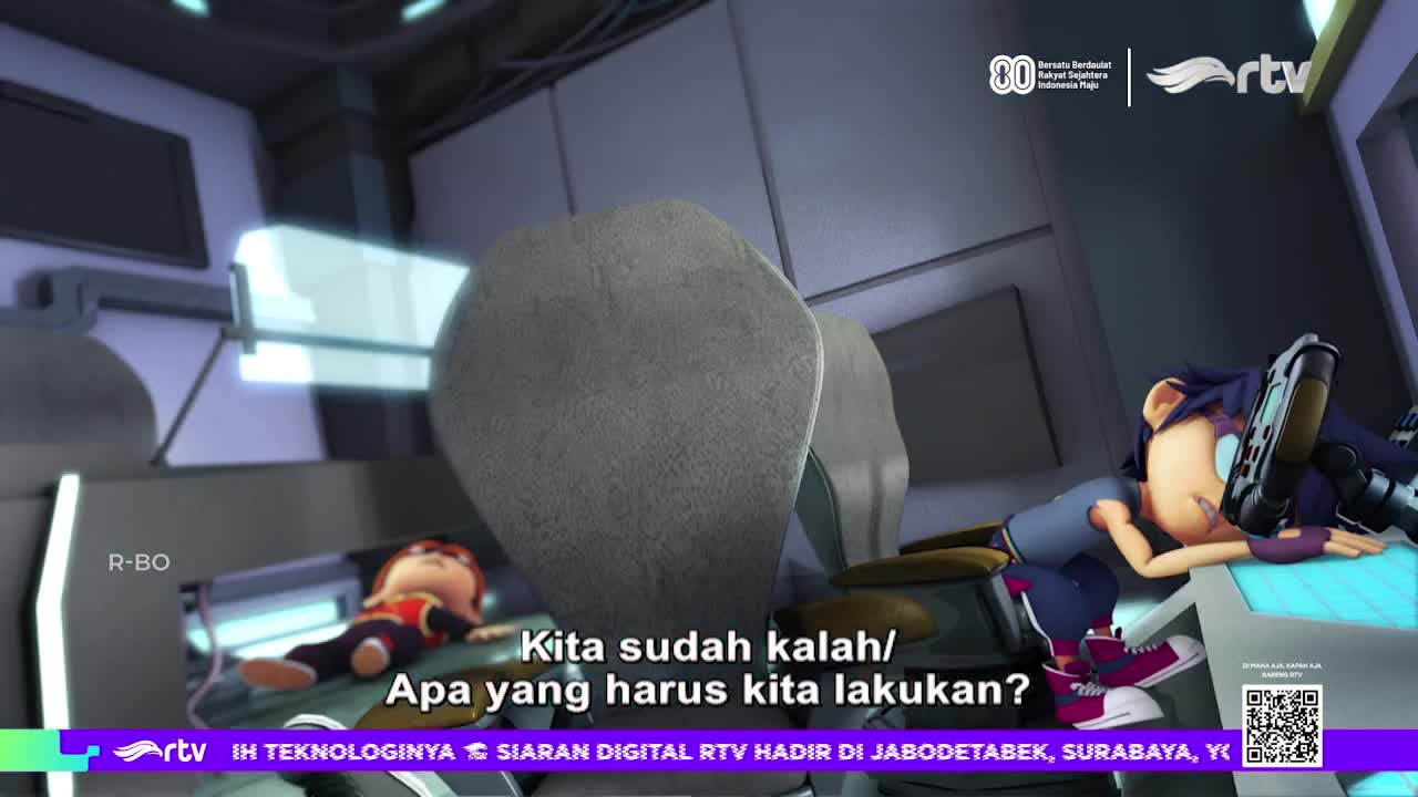 The scene is from a cartoon on Rajawali TV in Indonesia, with a character slumped over a console, a weapon in hand. Another character lies still in a nearby seat, and text on screen asks, "We've lost, what should we do?"
