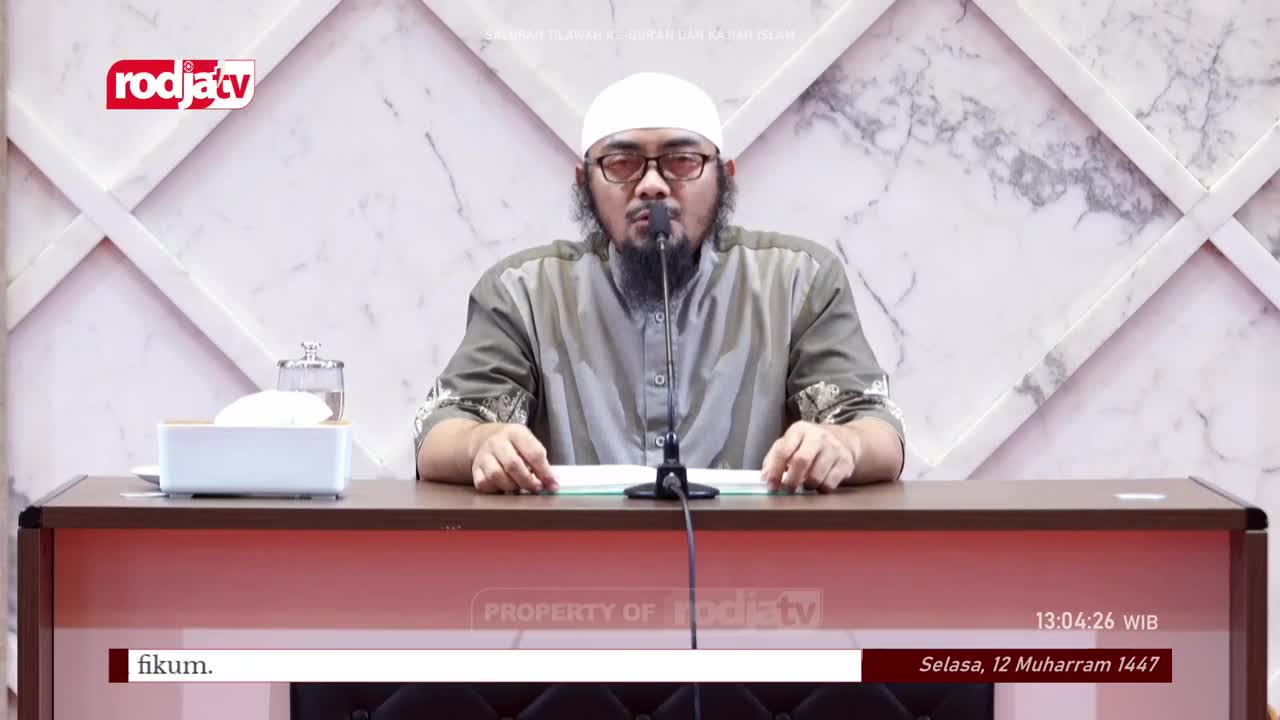 A man in a white cap and glasses speaks into a microphone, his hands resting on a book. The Rodja TV logo is visible in the corner, and the date is displayed at the bottom of the screen.
