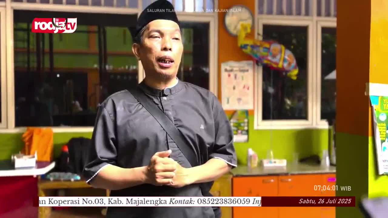 A man in a black shirt and cap speaks animatedly, his mouth open as he gestures with his hands. The Rodja TV logo is visible in the corner, and the date is displayed on the screen.
