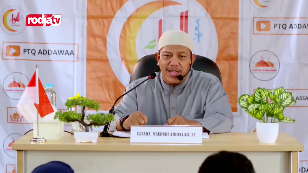 A man in a white cap speaks into a microphone, his hands gesturing as he addresses the audience. The Rodja TV logo sits in the corner, and the Indonesian flag stands on the table in front of him.
