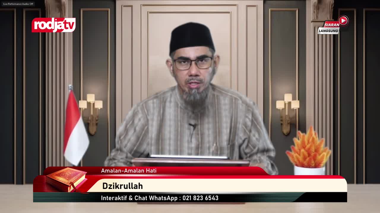 A man with a beard and glasses speaks directly into the camera from a Rodja TV studio. Behind him, the Indonesian flag and a decorative light fixture flank a backdrop with a stylized flame.

