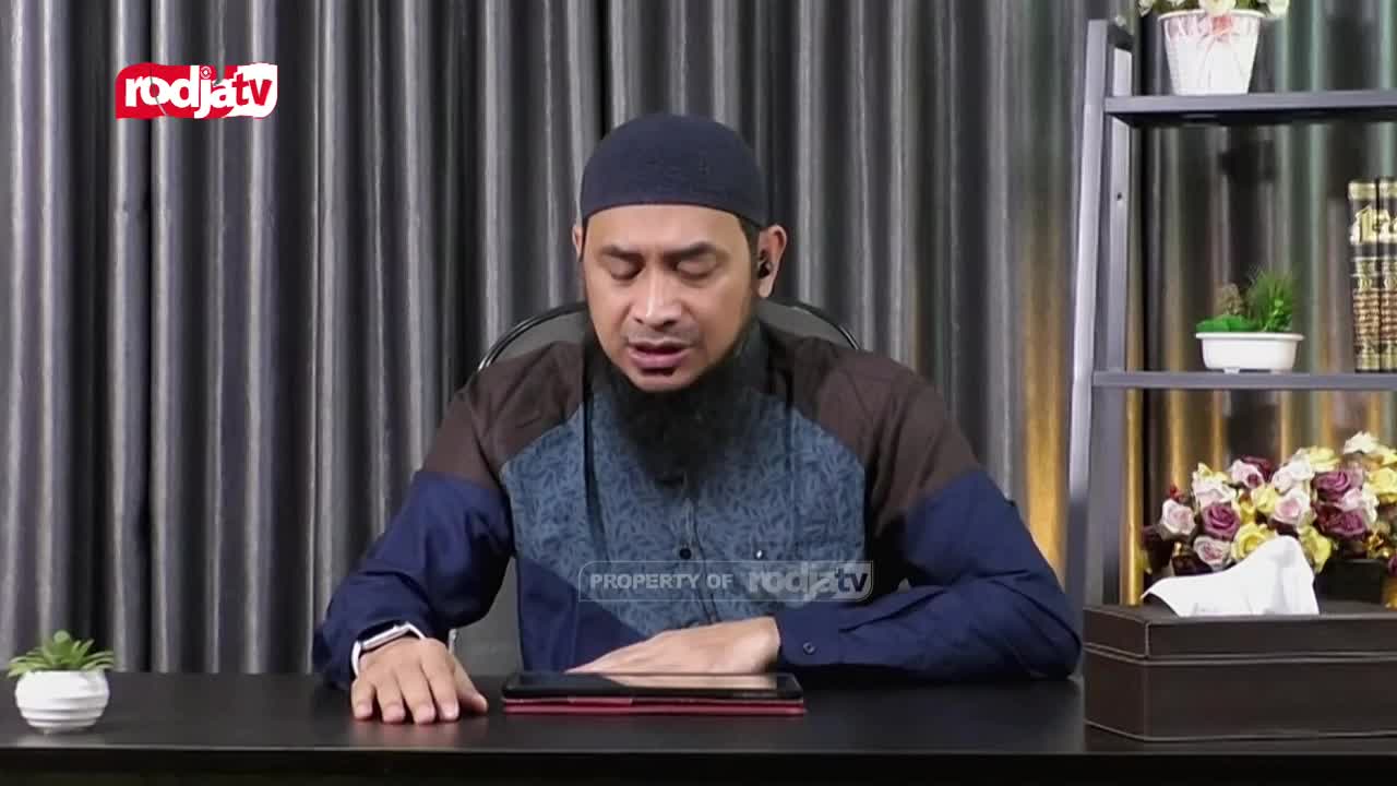 A man wearing a peci and a patterned shirt speaks with his eyes closed, his hands resting on a tablet. The Rodja TV logo appears in the corner of the screen.