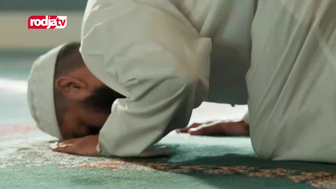 A man in a white peci and robe bows his head to the patterned carpet of a mosque. The Rodja TV logo appears in the upper left corner. A man in a white peci and robe bows his head to the patterned carpet of a mosque. The Rodja TV logo appears in the upper left corner.