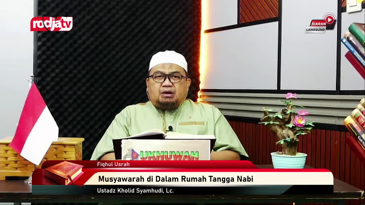 A man in a light green shirt and white cap speaks into a microphone, with the Indonesian flag to his left. A banner below him reads "Musyawarah di Dalam Rumah Tangga Nabi" and credits Ustadz Kholid Syamhudi, Lc. A man in a light green shirt and white cap speaks into a microphone, with the Indonesian flag to his left. A banner below him reads "Musyawarah di Dalam Rumah Tangga Nabi" and credits Ustadz Kholid Syamhudi, Lc.