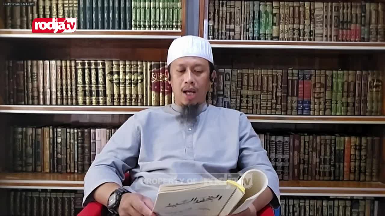 A man in a white peci and a light grey tunic sits in front of shelves packed with books, holding an open Arabic text. The Rodja TV logo appears in the corner, indicating this is a broadcast from Indonesia. A man in a white peci and a light grey tunic sits in front of shelves packed with books, holding an open Arabic text. The Rodja TV logo appears in the corner, indicating this is a broadcast from Indonesia.