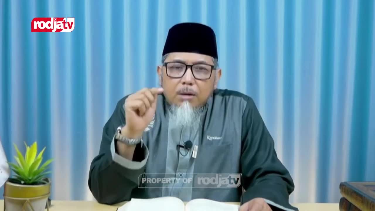 A man in a peci and glasses gestures with his right hand, speaking to the camera. The Rodja TV logo appears in the corner of the screen. A man in a peci and glasses gestures with his right hand, speaking to the camera. The Rodja TV logo appears in the corner of the screen.