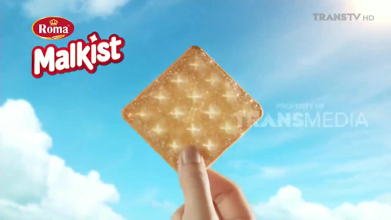 A hand holds a Roma Malkist cracker against a bright blue sky, the sun shining down. The Trans TV logo and "Property of Transmedia" are visible in the corner.
