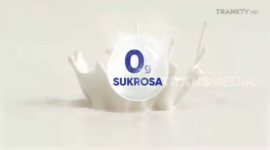 A splash of white liquid erupts, forming a crown shape around a floating circle. The circle, bearing the words "0g SUKROSA," hovers above the liquid on Trans TV.
