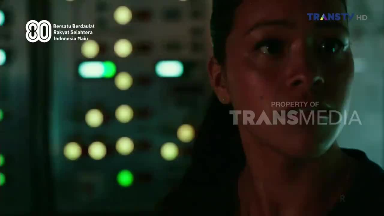 A woman stares intently, her face lit by the glow of the control panel behind her. The Trans TV logo and Indonesian text are visible in the corner of the screen.
