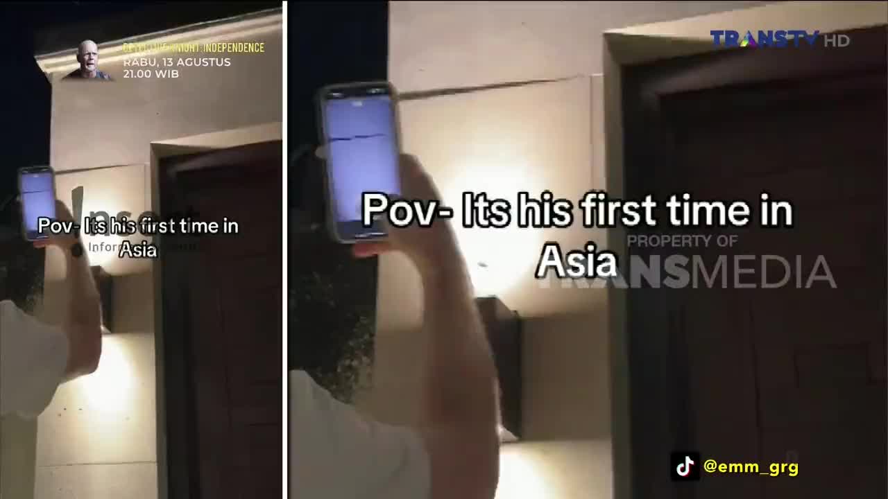 A person holds a phone up, presumably filming, in front of a building entrance. The Trans TV logo and a caption about a first-time visit to Asia are overlaid on the video.
