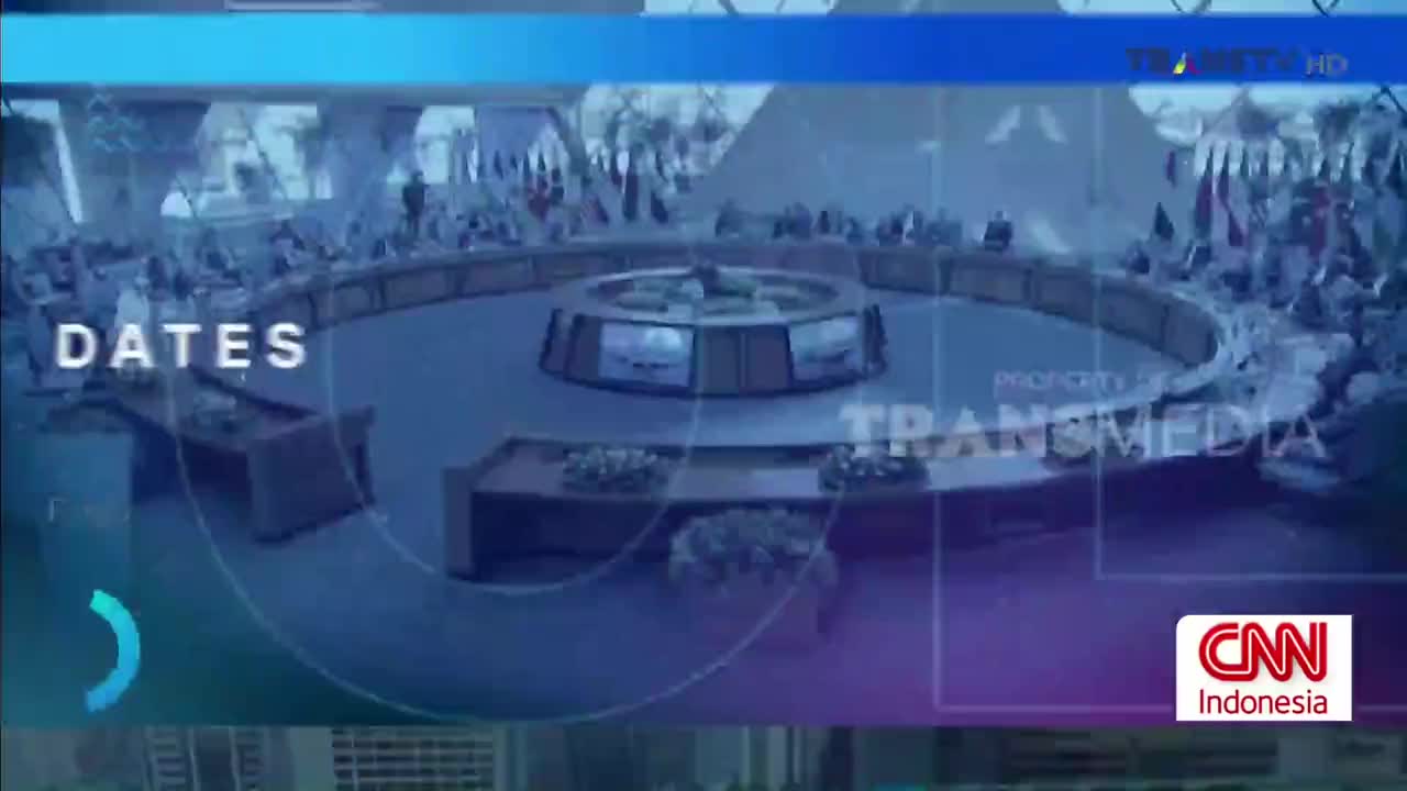 A conference is underway, with people seated around a large, circular table. The Trans TV logo and CNN Indonesia branding are visible on the screen.
