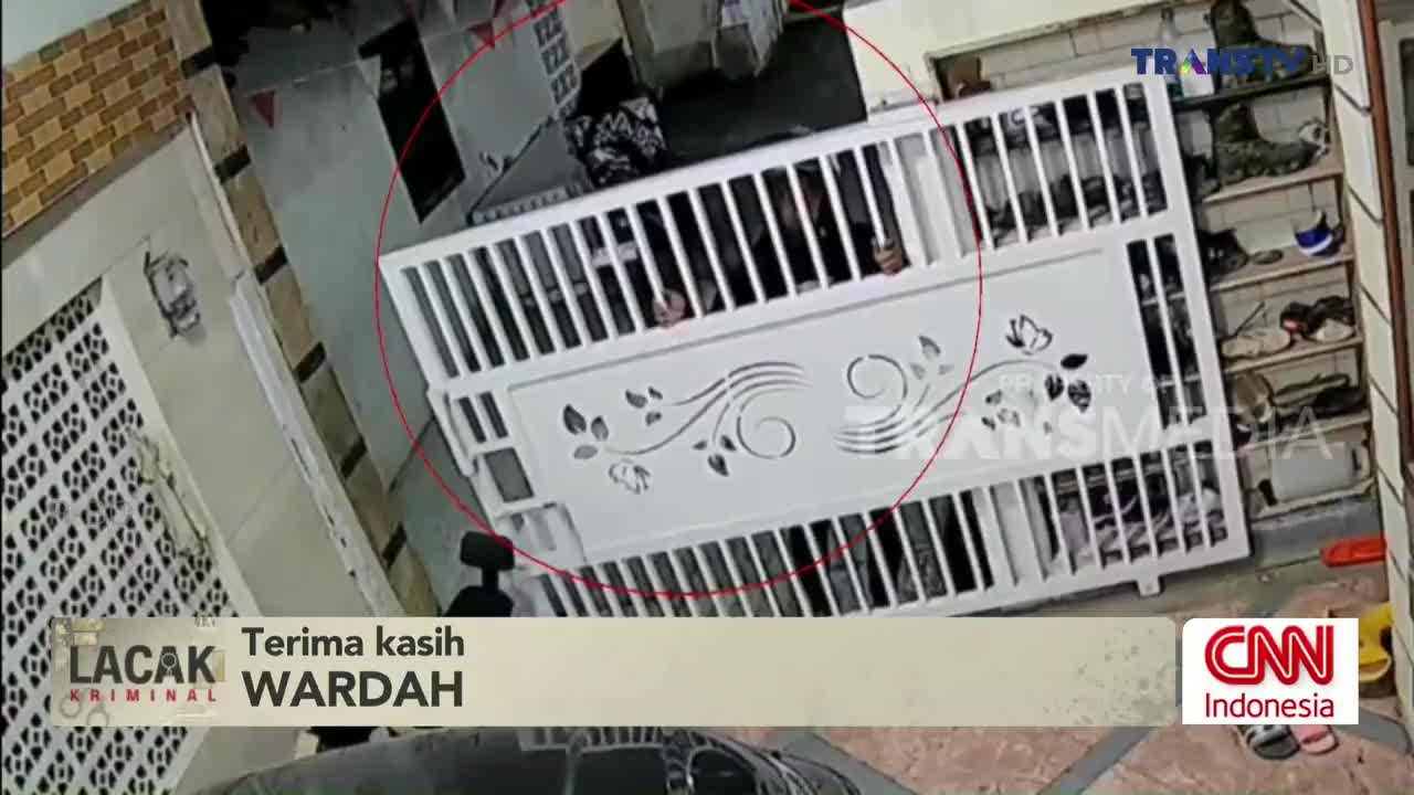 A person is visible behind a white gate, their hands gripping the bars. The scene is being broadcast on Trans TV, with a CNN Indonesia logo in the corner.
