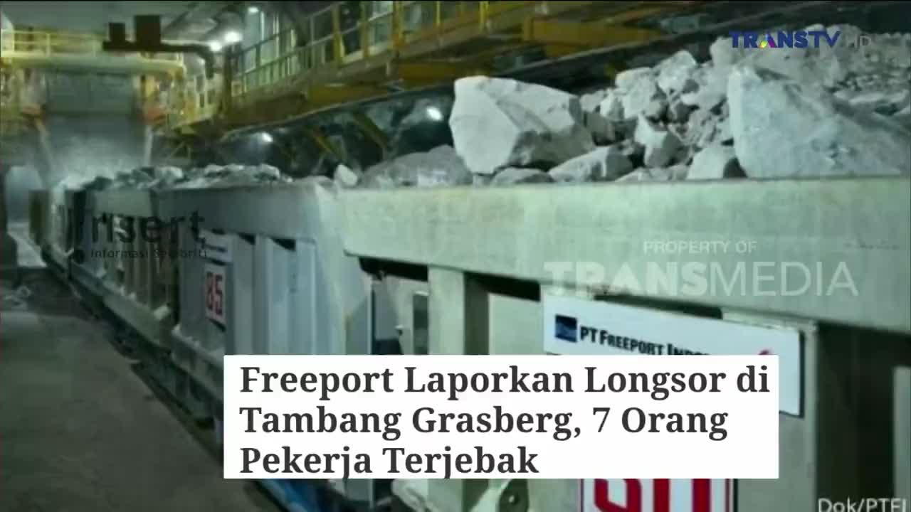 A train car is buried under large rocks, with a plume of dust rising around it. The Trans TV logo and a headline about a landslide at the Grasberg mine in Indonesia are visible.
