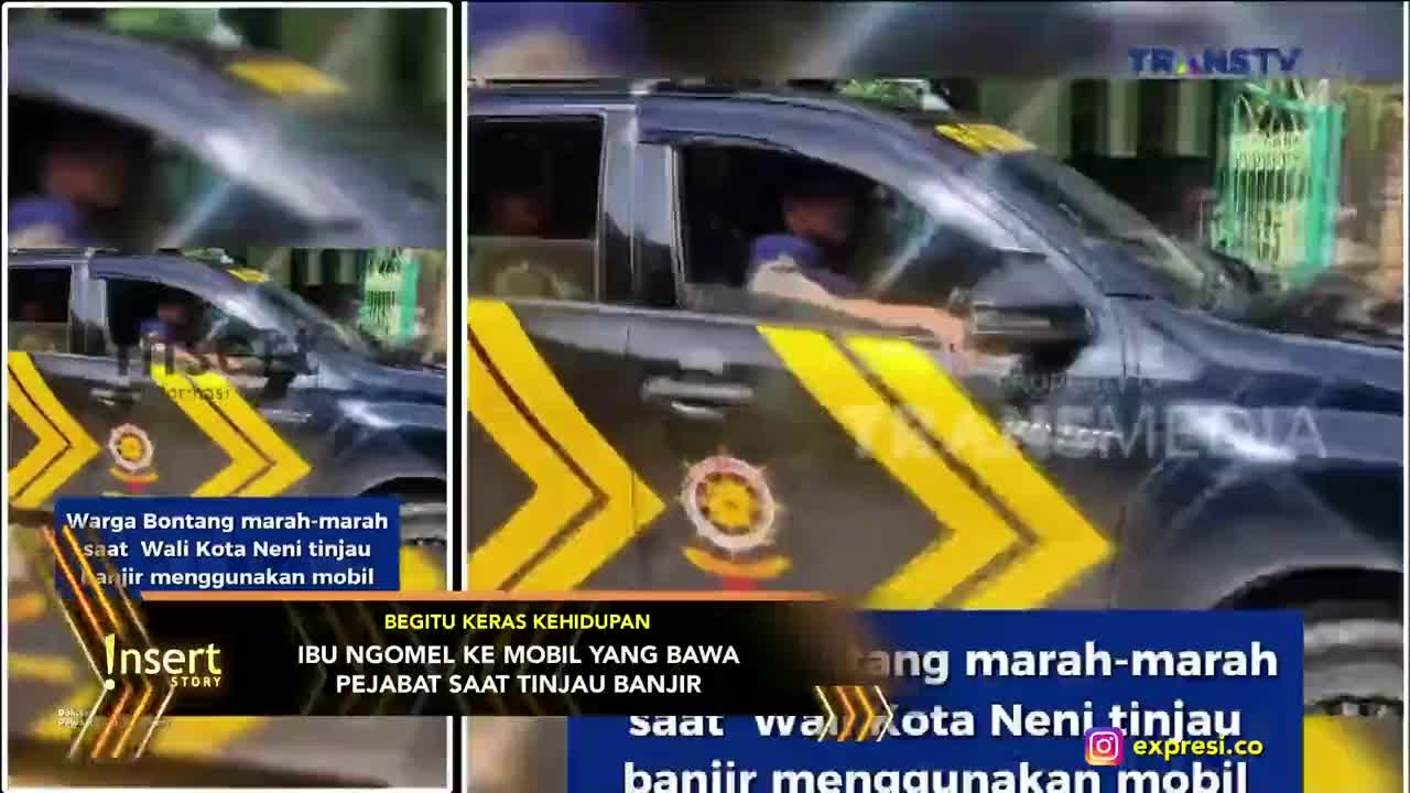 A dark vehicle with yellow chevron markings is moving slowly, the window down. A woman is gesturing angrily at the car, as reported by Trans TV.
