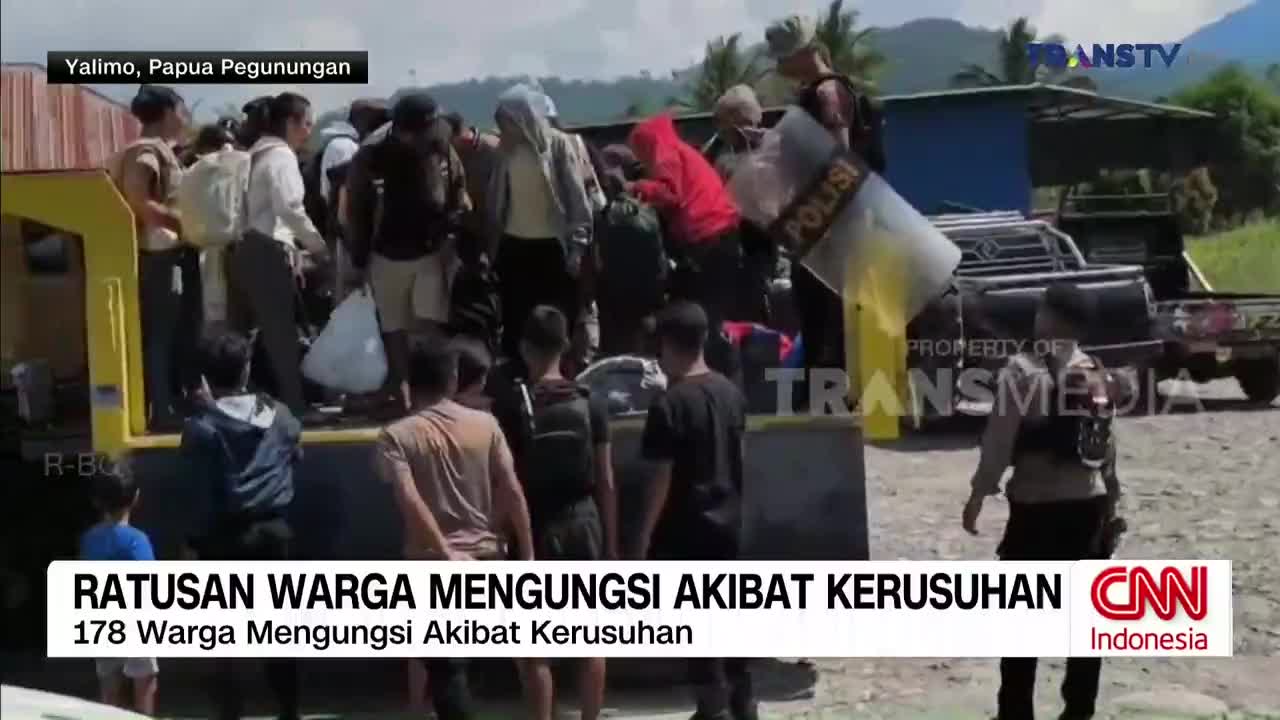 People are climbing out of a truck bed, some carrying bags, while police officers stand nearby with shields. A Trans TV logo is visible, and the CNN Indonesia logo is also displayed.
